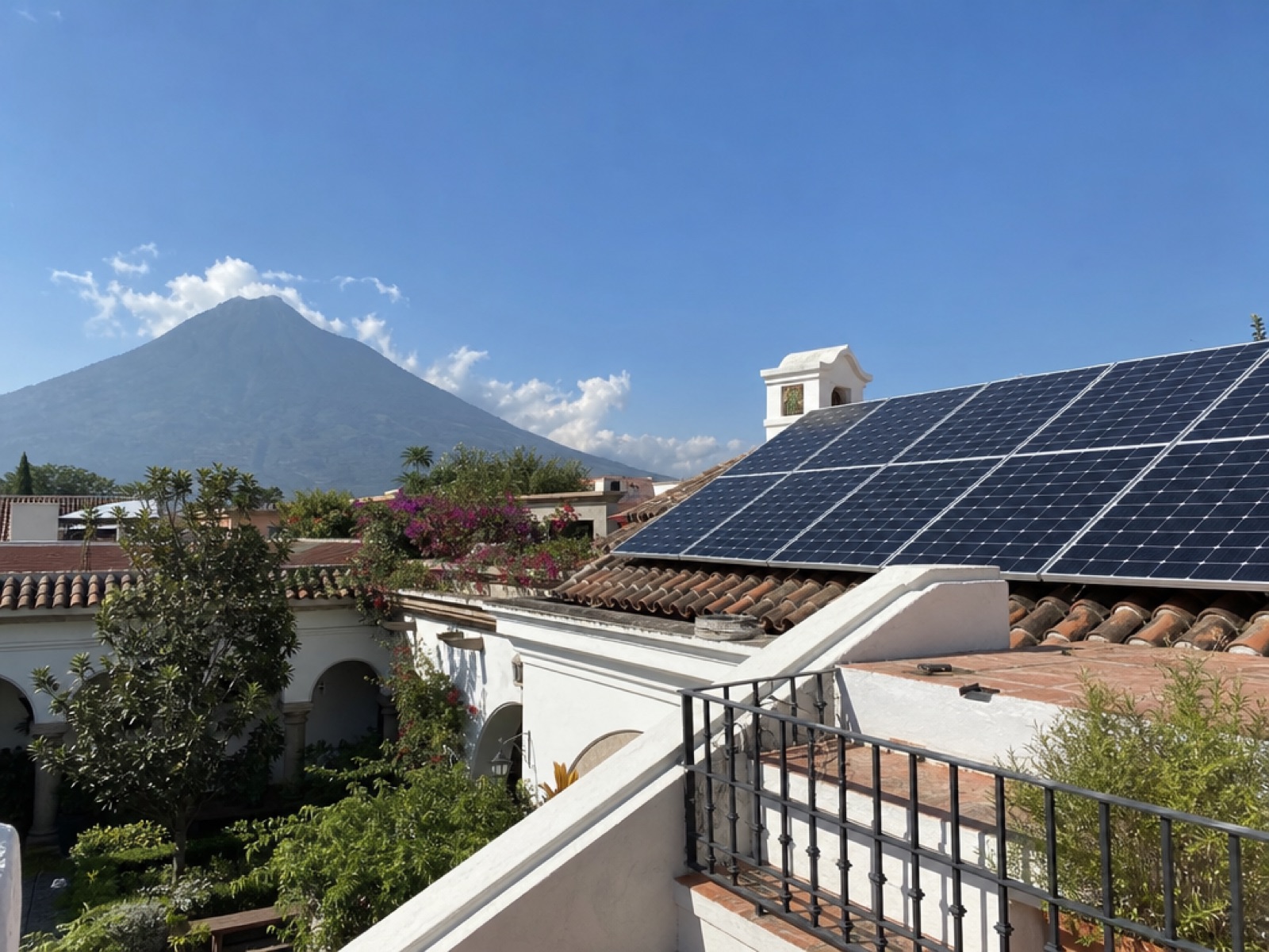 Rooftop solar panels installed on a colonial home in Antigua Guatemala with Volcán de Agua behind