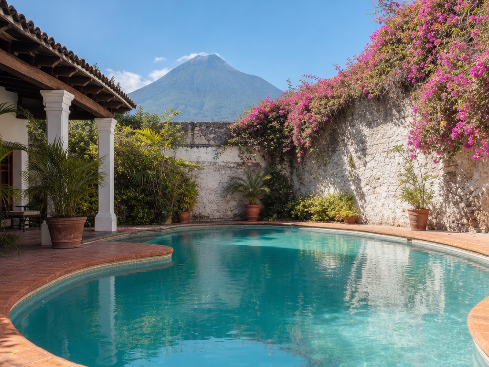 Private turquoise swimming pool in a walled colonial courtyard in Antigua Guatemala, with terracotta tile, pink bougainvillea and Volcán de Agua in the background